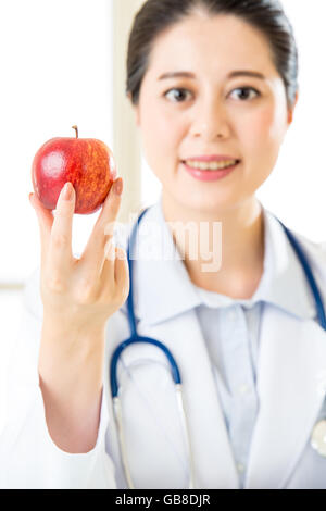 Junge asiatische Ernährungsberaterin hält einen Apfel, gesundes Essen Stockfoto