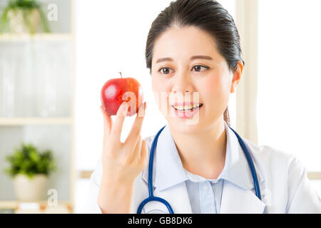 Junge asiatische Ernährungsberaterin hält einen Apfel, gesundes Essen Stockfoto