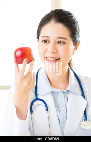 Junge asiatische Ernährungsberaterin hält einen Apfel, gesundes Essen Stockfoto