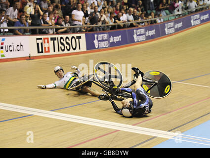 Jason Kenny (rechts) rutscht über die Ziellinie, um die Goldmedaille zu gewinnen, während seine Gegnerin Shane Perkins nach einem Sturz Meter von der Ziellinie im zurückgleitet, während die Fans beim Sprint-Finale der Männer während des UCI Track World Cup im Manchester Velodrome, Manchester, auf sich blicken. Stockfoto