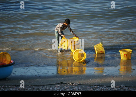 PHAN THIET, VIET NAM - FEB 3: Fischer waschen Kunststoffkorb durch Wasser am Strand von Phan Thiet, Vietnam am 3. Februar 2013 Stockfoto