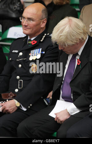 Der Bürgermeister von London, Boris Johnson, blickt auf ein Mobiltelefon, während er neben dem stellvertretenden Beauftragten der Metropolitan Police, Sir Paul Stephenson (links), beim jährlichen Metropolitan Police Memorial Service für Polizisten und Mitarbeiter sitzt, die im Rahmen ihrer Dienstzeit im Memorial Garden in der ihr Leben verloren haben Peel Centre, Hendon, London. Stockfoto