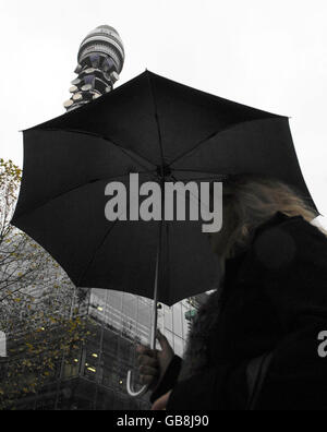 Eine Frau mit einem Regenschirm geht am Telecom Tower im Zentrum Londons vorbei. Stockfoto