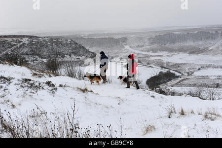 Hundespaziergänger im Schnee am Hole-of-Horcum im North Yorkshire Moors National Park, während eine arktische Wetterfront Großbritannien trifft. Stockfoto