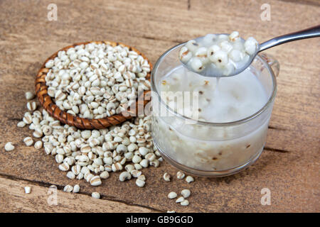 Job's Tears mit Kokosmilch in Glas und Job's Tears raw auf Holztisch. Thai Dessert. Löffel Dessert zeigen. Stockfoto