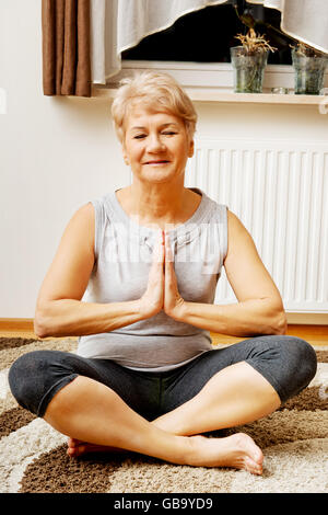 Ältere Frau beim Yoga im Wohnzimmer Stockfoto