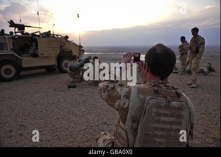 Kapitän Charles Robinson von der 1. Garde der Königinnen Dragoon macht ein Foto in der untergehenden Sonne seiner Truppen, während sie beobachten und versuchen, bei einem Feuerkampf zwischen den Taliban und der afghanischen Nationalarmee in der Nawar-Region der Provinz Helmand in Afghanistan dabei zu helfen, feindliche Truppen zu lokalisieren. Stockfoto