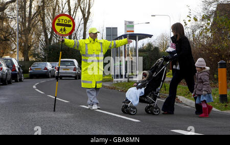 Kevin Simpson, ein Polizeibeamter, der die Schule durchquert, hilft einer Familie gegenüber in Southampton. Stockfoto