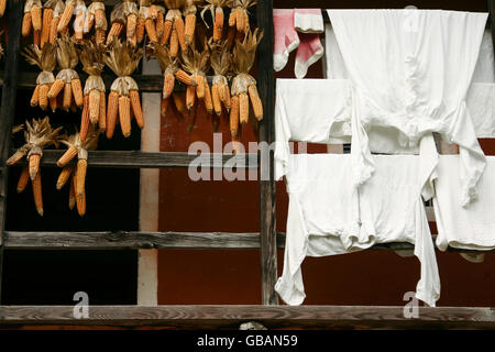 Ein Balkon von einem alten Bauernhaus im Freilichtmuseum Ballenberg in der Schweiz mit trockenen Mais und weiße Wäsche Stockfoto
