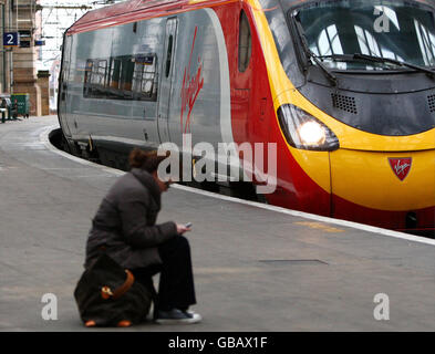 Ein Passagier wartet auf einen Virgin-Zug aus London, der am Hauptbahnhof von Glasgow ankommt, nachdem den Reisenden neue und verbesserte Zugverbindungen mit der Einführung eines neuen Fahrplans auf der London nach Scotland West Coast Main Line versprochen wurden, wo gerade ein Upgrade von 9 Milliarden abgeschlossen wurde. Stockfoto