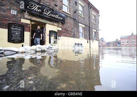 Ein Mann beobachtet, wie das aufsteigende Flutwasser aus dem River Ouse nach sintflutartigen Regenfällen am Wochenende an einem Pub in York vorbeifließt. Stockfoto