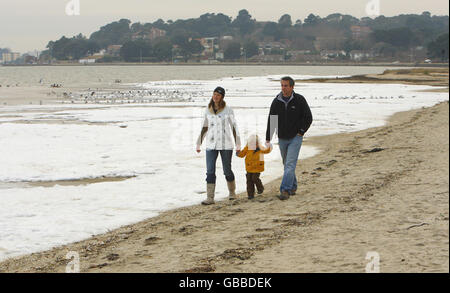 Nick und Clina Hopwood und ihr Sohn Tom laufen am Strand entlang in der exklusiven Sandbanks-Gegend von Poole, wo das Meer heute aufgrund der extrem niedrigen Temperaturen, die die Gegend treffen, erfroren ist. Stockfoto