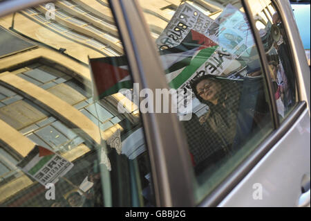 Die Demonstranten spiegeln sich in einem Autofenster, wenn sie durch das Zentrum von Bristol marschieren, während sie gegen die Bombenanschläge in Gaza im Nahen Osten protestieren. Stockfoto