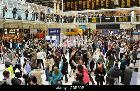 Eine riesige Menge von Tänzern unterhalten Pendler, während sie während der Dreharbeiten zu einem Handy-Werbespot tanzen, an der Liverpool Street Station in London. Stockfoto