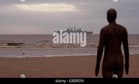 HMS Ark Royal geht an den Gormley Statuen in Crosby Beach, Merseyside vorbei, bevor sie in Liverpool anlegt. Stockfoto