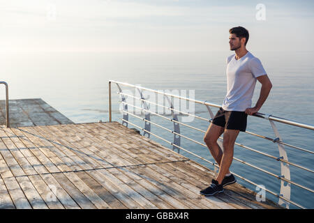 Entspannte junge Sportler stehen am Pier in der früh Stockfoto