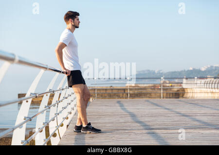 Profil von gut aussehenden jungen Mann stehend auf Holz-Terrasse am Meer Stockfoto