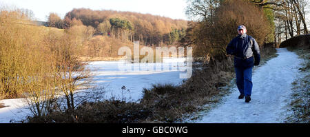 Ein Mann geht in der Nähe des teilweise gefrorenen Fewston Reservoir, in der Nähe von Harrogate, North Yorkshire. Stockfoto