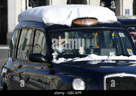 Ein schneebedecktes schwarzes Londoner Taxi fährt um den Parliament Square im Zentrum Londons. Stockfoto