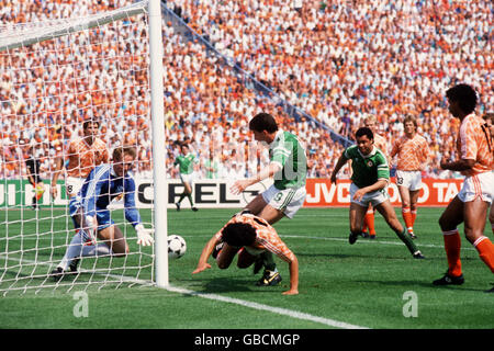 Irlands John Aldridge (c) wird vom holländischen Torhüter Hans geleugnet Van Breukelen (l) als Teamkollege Paul McGrath (r) Rennen in Stockfoto