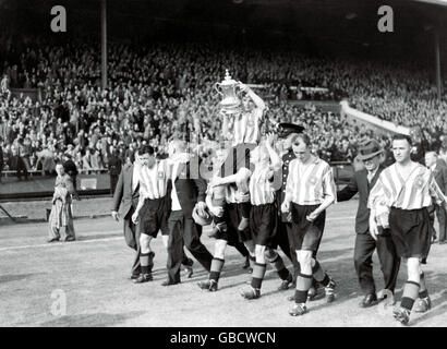 Sunderland-Kapitän Raich Carter zeigt den FA Cup als er Wird rund um den Platz von seinen triumfhenden Teamkollegen geleitet Stockfoto