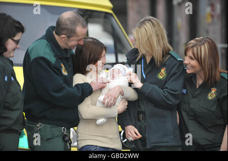 Cordelia Nolan, 25, mit ihrem 12 Wochen alten Baby Emrys und den Sanitätern und Hilfskanteln, die Frau Nolan dabei halfen, das Leben ihres Babys viermal in 10 Minuten zu retten. Stockfoto