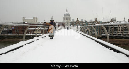 Fußgänger laufen über die Millennium Bridge über die Themse mit der St. Paul's Cathedral im Hintergrund, während im Zentrum Londons weiterhin starker Schnee fällt. Stockfoto