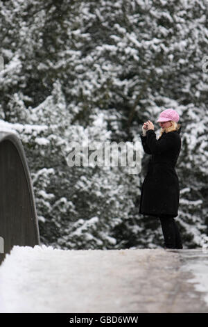 Eine Frau fotografiert die verschneite Szene von einer Brücke über den Fluss Cam in Cambridge, Cambridgeshire. Stockfoto