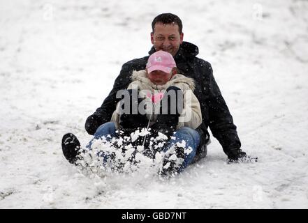 Howard Desmond hat Spaß auf seinem Schlitten mit seiner Tochter Jasmine Desmond, 8, in Chelmer Valley, Chelmsford, Essex, Bei starkem Schneefall. Stockfoto