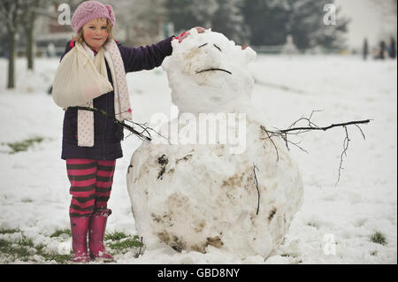 Liberty Walker, 9, die sich vor ein paar Tagen durch einen Sturz auf das Eis am Arm verletzt hat, ist nach einer Nacht starken Schneefalls zurück in den Schneemännern im Victoria Park, Windmill Hill, Bristol. Stockfoto