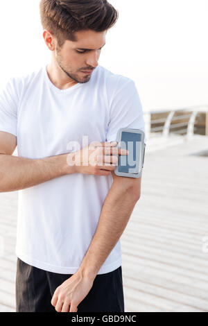 Konzentrierte sich junge Sportler mit Smartphone in Armbinde im freien Stockfoto