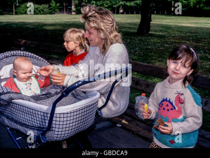 Mutter mit ihren drei Töchtern auf einem Spaziergang im Park, Prag, Tschechische Republik Familie Baby im Kinderwagen Frau drei Kinder Stockfoto