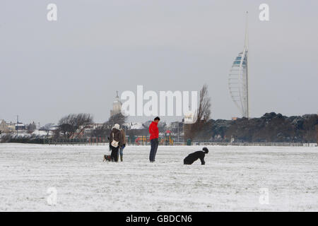 Der Spinnaker Tower steht über Hundespaziergängern auf dem Southsea Common in Portsmouth, während starker Schneefall Großbritannien trifft. Stockfoto
