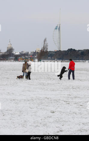 Der Spinnaker Tower steht über Hundespaziergängern auf dem Southsea Common in Portsmouth, während starker Schneefall Großbritannien trifft. Stockfoto