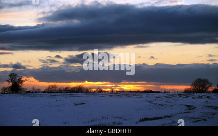 Die Sonne untergeht über schneebedeckten Feldern in der Nähe von Wotton-under-Edge, Gloucestershire. Stockfoto