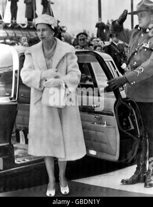 Königin Elizabeth II. Wird von einem Mitglied der Royal Canadian Mounted Police begrüßt, das sich in der berühmten Uniform der Streitkräfte tadellos herausstellte, als sie von einem Auto in St. John's, Neufundland, dem Ausgangspunkt ihrer Tour durch Kanada mit dem Herzog von Edinburgh, kommt. Stockfoto