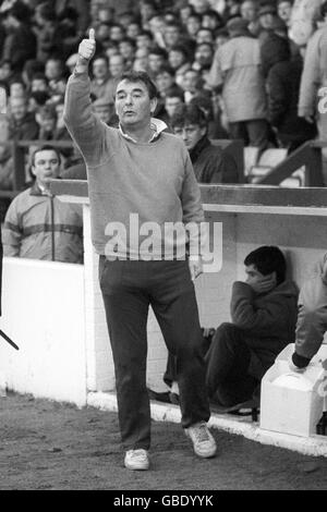 Nottingham Forest Manager Brian Clough gibt seinem Team während des Spiels einen Daumen nach oben, während sein Sohn Nigel Clough auf der Bank schmort. Stockfoto