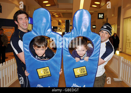 Nathan Hines (links) und Simon Webster (rechts) helfen den Jugendlichen Jack Parker (7) (zweite links) und Megan Auld (5) bei einem Rugby-Tag im Ocean Terminal, Edinburgh, durch ein Hindernis. Stockfoto