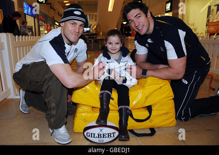 Nathan Hines (rechts) und Simon Webster (links) unterschreiben einen schottlandspitze für Megan Auld (5) während eines Rugby-Tages am Ocean Terminal in Edinburgh. Stockfoto