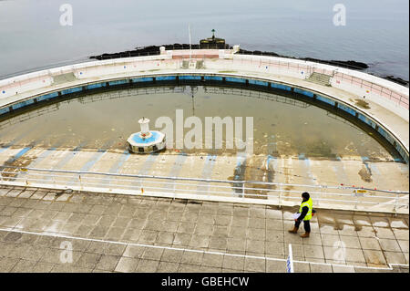 Ein Arbeiter geht am Pool von Tinside Lido, Plymouth Hoe, vorbei, wo Renovierungsarbeiten stattfinden. Stockfoto