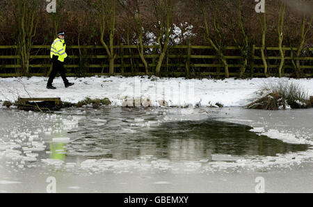 Ein Polizeibeamter geht an dem Loch in einem Teich vorbei, in dem ein sechsjähriger Junge einfiel und gestern ertrank, nachdem er auf dem Eis in Streethouse bei Pontefract gegangen war. Stockfoto