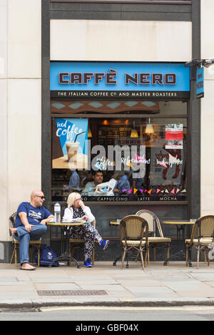 Ein Paar, das sich im Juli vor dem Café Caffé Nero in London, Großbritannien, entspannen kann Stockfoto