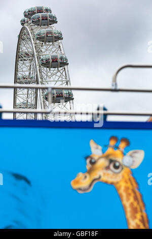 Top of London Eye Rad unter bewölktem atmosphärischem Himmel mit Giraffe auf der Seite des Busses in London UK im Juli Stockfoto