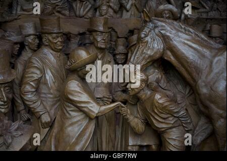 Nahaufnahme eines von zwei Bronzereliefs, die zeigen, dass die Königin Mutter während des Blitzes Familien besucht, die von Bomben obdachlos gemacht wurden, und die Rennen in Ascot genießt. Die Schnitzereien wurden in die Seiten eines Denkmals für die Königin Mutter eingearbeitet, das heute in der Mall im Zentrum von London enthüllt wurde. Stockfoto