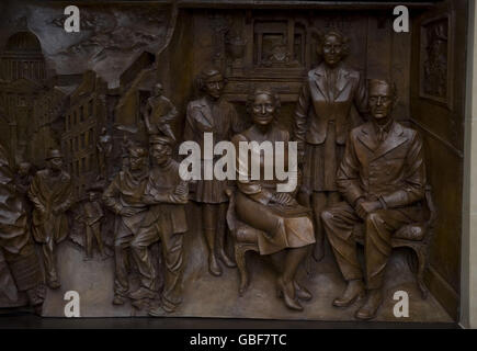Nahaufnahme eines von zwei Bronzereliefs, die zeigen, dass die Königin Mutter während des Blitzes Familien besucht, die von Bomben obdachlos gemacht wurden, und die Rennen in Ascot genießt. Die Schnitzereien wurden in die Seiten eines Denkmals für die Königin Mutter eingearbeitet, das heute in der Mall im Zentrum von London enthüllt wurde. Stockfoto