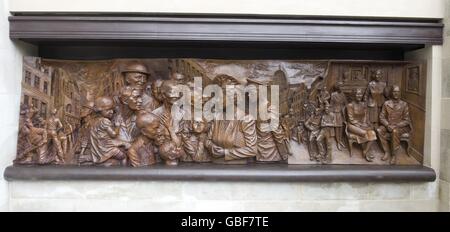 Nahaufnahme eines von zwei Bronzereliefs, die zeigen, dass die Königin Mutter während des Blitzes Familien besucht, die von Bomben obdachlos gemacht wurden, und die Rennen in Ascot genießt. Die Schnitzereien wurden in die Seiten eines Denkmals für die Königin Mutter eingearbeitet, das heute in der Mall im Zentrum von London enthüllt wurde. Stockfoto