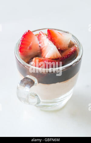 Schokoladenmousse garniert mit Erdbeeren Obst im Glas auf weißem Hintergrund Stockfoto