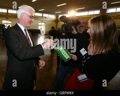 Bundeskanzlerin Alistair Darling legt Geld für Comic-Hilfe in eine Sammelbox, die der Tanzlehrer des P.E. Departments Jo Emery während eines Besuchs der Millais School in Horsham, West Sussex, im Vorfeld des G20-Finanztreffens am Wochenende in der Grafschaft gehalten hat. Stockfoto