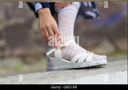 kleines Mädchen auf ihre Sandalen im freien Stockfoto