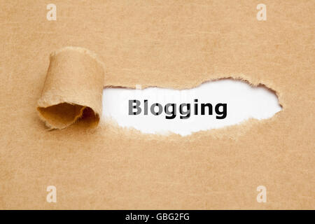 Das Wort Blogging erscheint hinter braunes Papier zerrissen. Stockfoto
